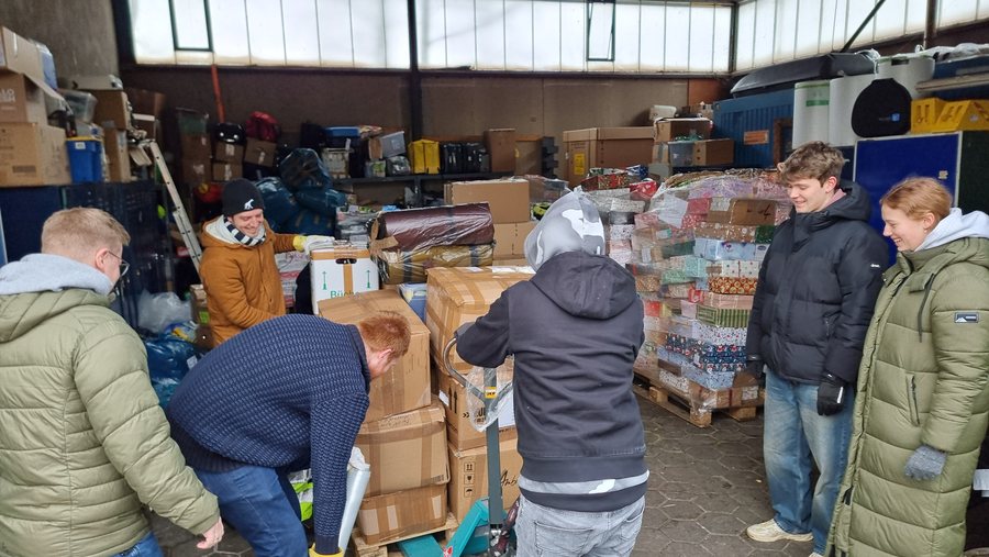 Junge Helferinnen und Helfer bewegen Spendenkartons mit dem Hubwagen im Lager in Hamburg-Stellingen